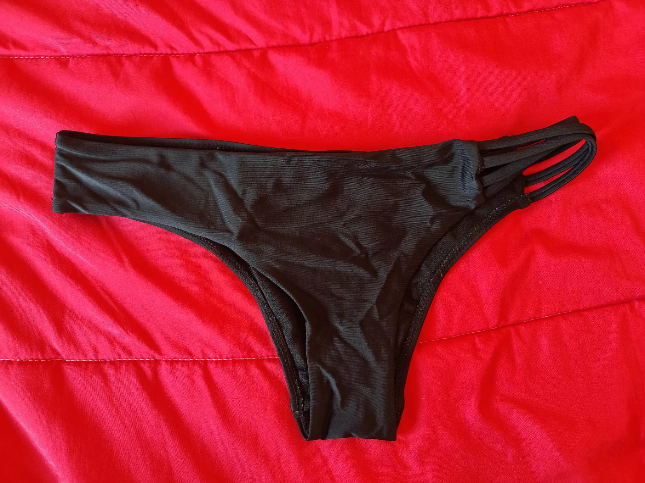 Cueca estilo bikini preta com um design moderno e detalhe de tiras.